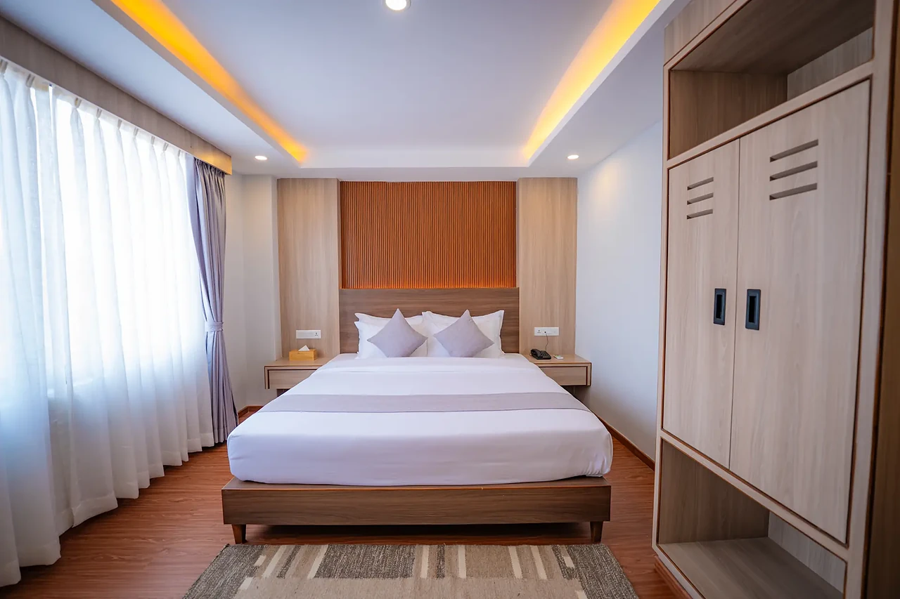 Hotel Sampada Deluxe Room with a king bed and warm timber finishes