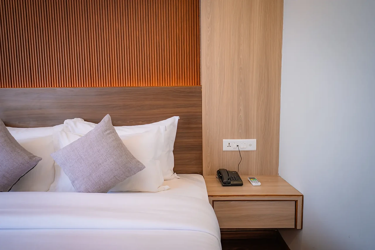 Deluxe Room bed and bedside table at Hotel Sampada