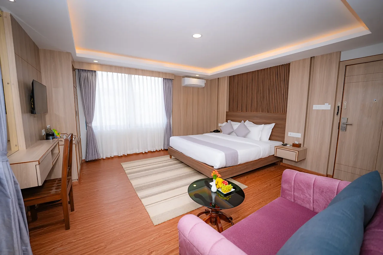 Hotel Sampada suite with a lounge sofa, king bed and slatted timber headboard