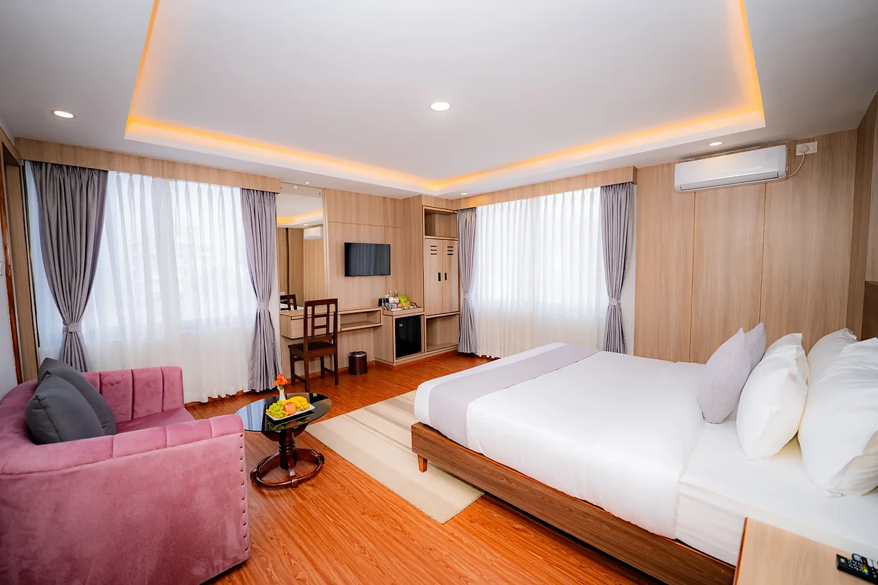 Corner suite with armchair and king bed at Hotel Sampada