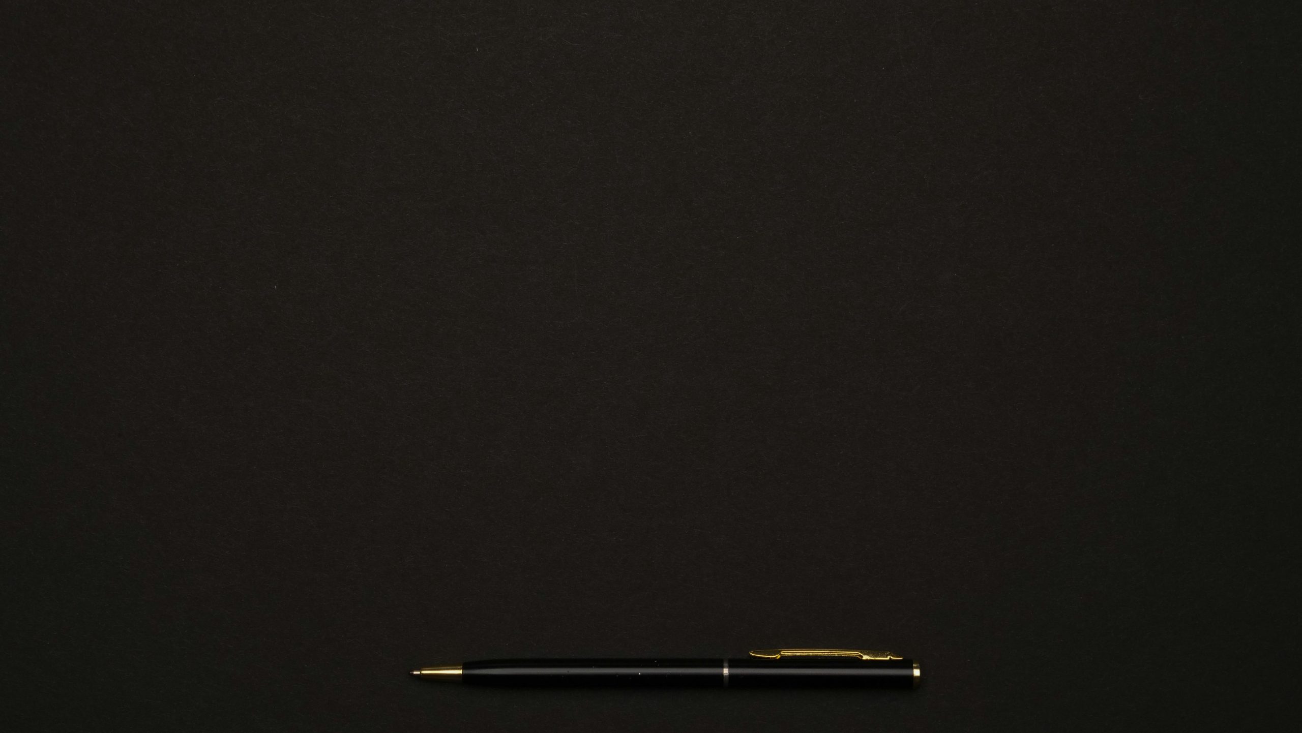 A sleek black pen placed on a minimalist dark background, perfect for professional presentations.
